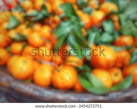 Blurred picture of small oranges with leaves on a basket for background

