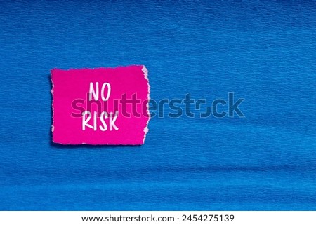 No risk written on ripped pink paper with blue background. Conceptual no risk symbol. Copy space.