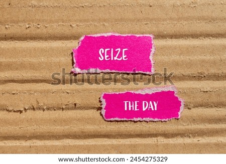 Seize the day words written on ripped pink paper with cardboard background. Conceptual seize the day symbol. Copy space. Royalty-Free Stock Photo #2454275329
