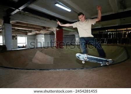 Wide motion blur shot of gen Z guy practicing trick while riding bowl in skateboard park, copy space