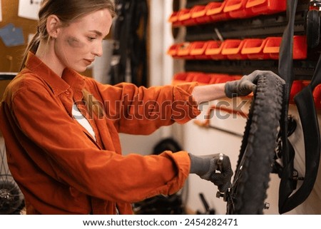 A girl mechanic repairing a bicycle in a workshop or garage checks a wheel for installation. Bike workshop interior