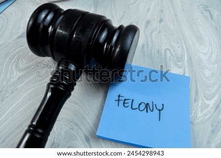 Concept of Felony write on sticky notes with gavel isolated on Wooden Table. Royalty-Free Stock Photo #2454298943