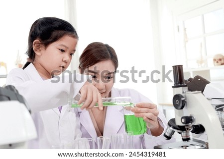 Happy young scientist kid girl in lab coats using lab equipment for study in school laboratory. Asian female teacher teaching schoolgirl child to do science experiments. Kid learning science education