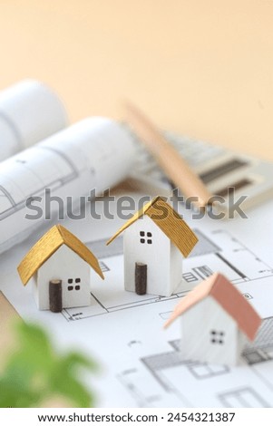 Image of thinking about purchasing a home using a miniature house and blueprints