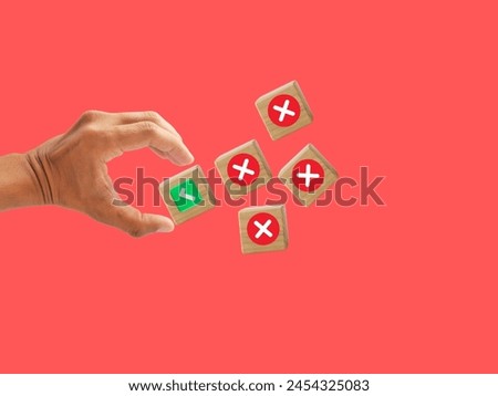 A male hand selecting wooden blocks featuring a right tick mark symbol, set against a red background, and providing room for a word. This represents a company concept.