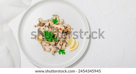 Rapana clam meat with oil, spices and greens. Healthy seafood is rich in omega. Marine decor, hard light, dark shadow, white plaster background, flat lay, banner format Royalty-Free Stock Photo #2454345945
