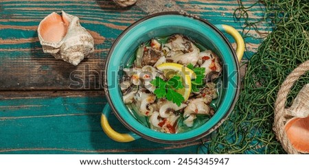 Rapana clam meat with oil, spices and greens. Healthy seafood rich of omega. Marine decor, hard light, dark shadow, old wooden boards, banner format Royalty-Free Stock Photo #2454345947