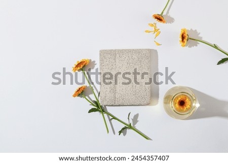 Blank white background with gray brick podium decorated and fresh calendula flowers for cosmetic presentation. Calendula contains the safest, most benign and gentle skin care ingredients. Top view