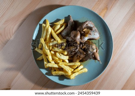 Fried quails with French fries on a white plate, a classic Portuguese dish. The quails are golden-brown and crispy, complemented by a generous serving of golden French fries for a hearty meal.