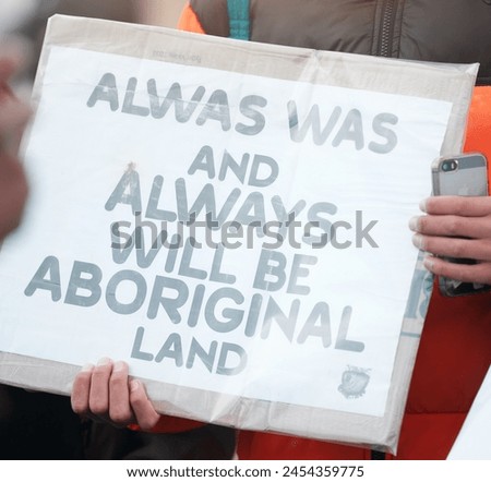 Person, protest and aboriginal with support, march and sign with demands, human rights and freedom. Cardboard, holding paper and indigenous with group in street, Australia and event for justice Royalty-Free Stock Photo #2454359775
