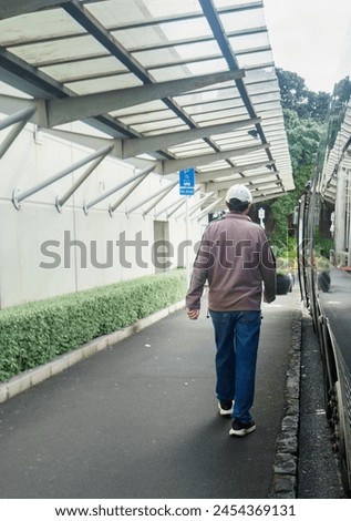 Man walking to the bus stop on an overcast day. Vertical format. Royalty-Free Stock Photo #2454369131