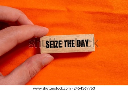 Seize the day words written on wooden block with orange background. Conceptual seize the day symbol. Copy space. Royalty-Free Stock Photo #2454369763