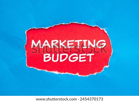 Marketing budget words written on ripped blue paper with red background. Conceptual marketing budget symbol. Copy space.