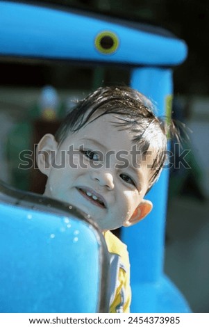 Hang Haung, Hong Kong, Asia - 07 24 2011 : Exterior photo of handsome cute charming adorable baby kid child children boy playing play in water from an small blue inflatable swimming pool home terrace