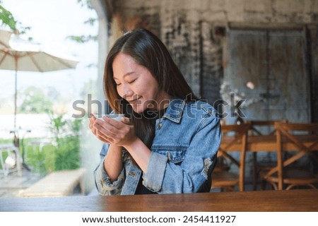 Portrait image of a beautiful young asian woman smelling and drinking hot coffee