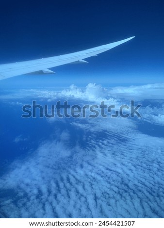 A view from an airplane, clouds above the ocean, airplane wing visible. Aerial picture of the ocean