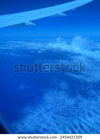 A view from an airplane, clouds above the ocean, airplane wing visible. Aerial picture of the ocean