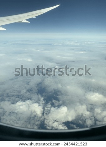 A view from an airplane, thick clouds above the ocean, airplane wing visible. Beautiful picture of the sky
