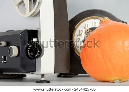 Halloween movie concept. Horror movie time. Film projector, pumpkin and clock