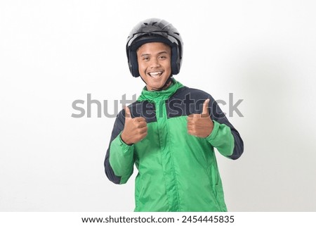 Portrait of Asian online taxi driver wearing green jacket and helmet showing good job sign, thumb up. Isolated image on white background