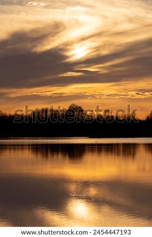 The sky and the lake are red-tinged during sunset, a beautiful sunset on the lake in early spring Royalty-Free Stock Photo #2454447193