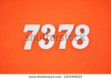 The number 7378 is made from white painted wood placed on a background of orange paper.