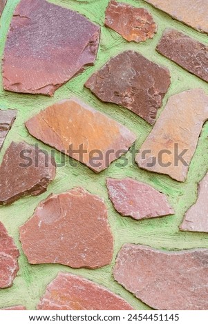 It is the photo of colorful stones on green background. Its close up of multicolored stone wall of building. It is photo of mosaic tile floor. It's view of wall texture.