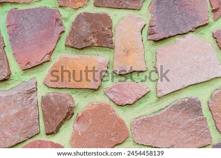 It is the photo of the colorful stones on the green background. Its close up of multicolored stone wall of building. It is photo of mosaic tile floor. It's view of wall texture.