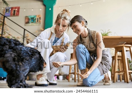 Two women sitting on floor, engrossed in watching a bird.