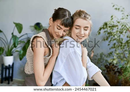 Two women sharing a heartfelt hug in an art-filled space. Royalty-Free Stock Photo #2454467021