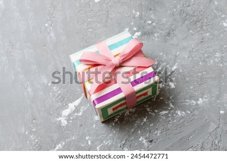 wrapped Christmas or other holiday handmade gift box in color paper with ribbon on colored background. Present box, decoration of gift on colored table, top view with copy space.