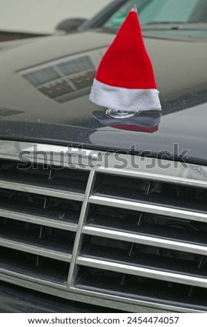 A Santa hat decoratively placed on the hood of a well-known car manufacturer.
