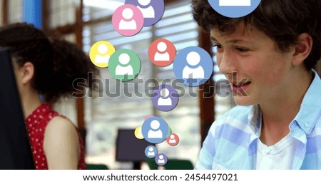 Image of people social media icons over smiling schoolboy using computer during class at school. Global science learning education concept digitally generated image.