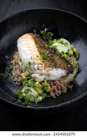 Fried skrei cod fish filet with avocado cream and boiled rice served as close-up on Nordic design plate with copy space 