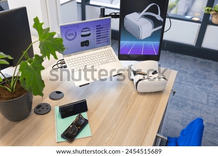 Desk with laptop displaying graphs and VR tech in contemporary business office. Various gadgets surrounding workspace, enhancing the tech-savvy environment, unaltered
