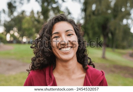 Portrait of native american woman smiling on camera with city park in background - Indigenous girl outdoor