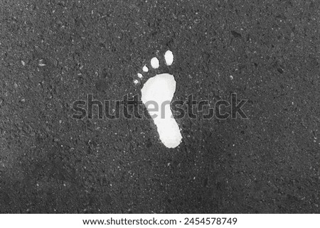 White paint of footsteps on the asphalt road .  Royalty-Free Stock Photo #2454578749
