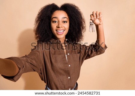 Photo of cheerful girl with perming coiffure wear brown blouse making selfie hold keys in arm isolated on pastel color background