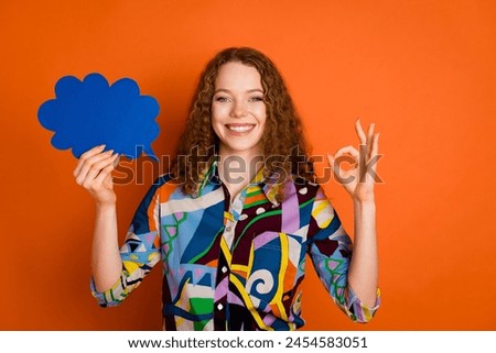Photo of cute cheerful girl wear stylish print clothes paper card okey sign empty space isolated on orange color background