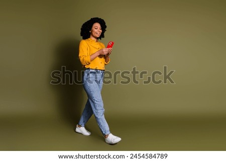 Full size photo of nice young woman use phone walk wear yellow shirt isolated on khaki color background