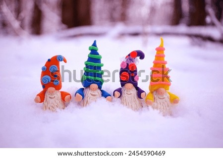 Figurines of colorful dwarfs made of plasticine. New Year decorations on a background of snow.
