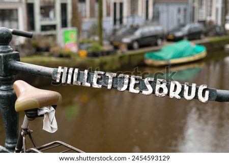 Hilletsjesbrug street name written on big individual metal letters decals pieces welded to bar of rail railing bridge walkway street crossover painted white green bike bicycle seat cloth canal boat