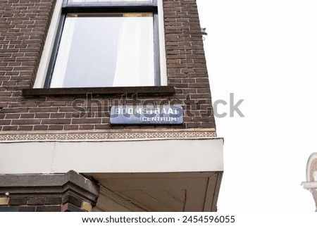 Corner edge of brick building in Amsterdam with blue metal street name sign above decorative pattern border Boomstraat (Centrum) street name in parentheses translation "centre" dutch to english 