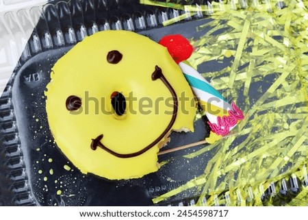 Yellow donut and paper birthday hat. Golden and black background. Happy. Smile. Joy.