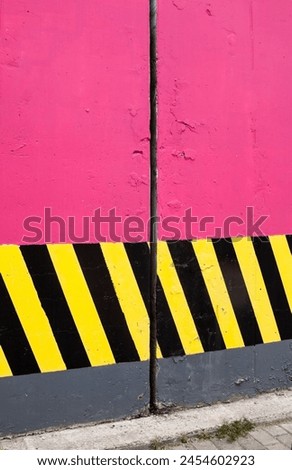 Pink concrete columns with black and yellow safety stripes.
