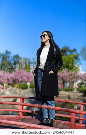 A stylish Korean or Japanese woman walks through the park, exuding beauty and grace amidst spring blooms.