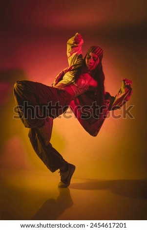 A woman is dancing in a room with a yellow background. Urban dancer concept.