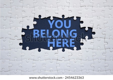 You belong here symbol. White puzzle with words You belong here. Beautiful deep blue background. Business and You belong here concept. Copy space.