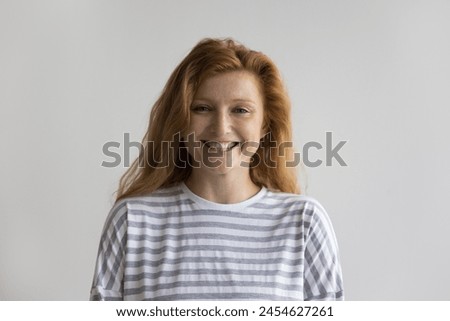 Happy millennial red-headed woman in casual shirt, laughing look at camera posing on gray wall studio background, having charming white-toothed smile, advertising professional dental clinic services