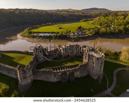 Sunset illuminates the historic ruins of a medieval castle beside a serene river